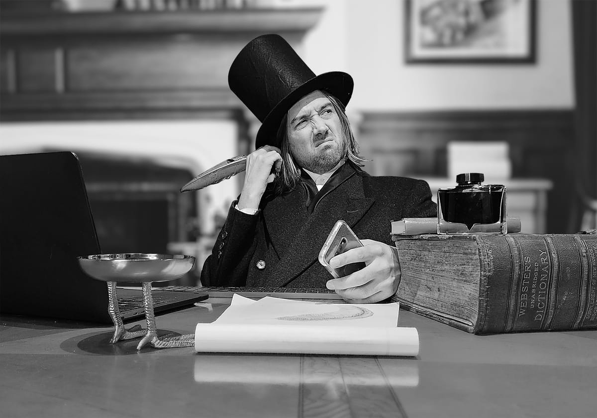 A silly picture of Tom George in a top hat and jacket, at a fancy desk with an overly large dictionary.